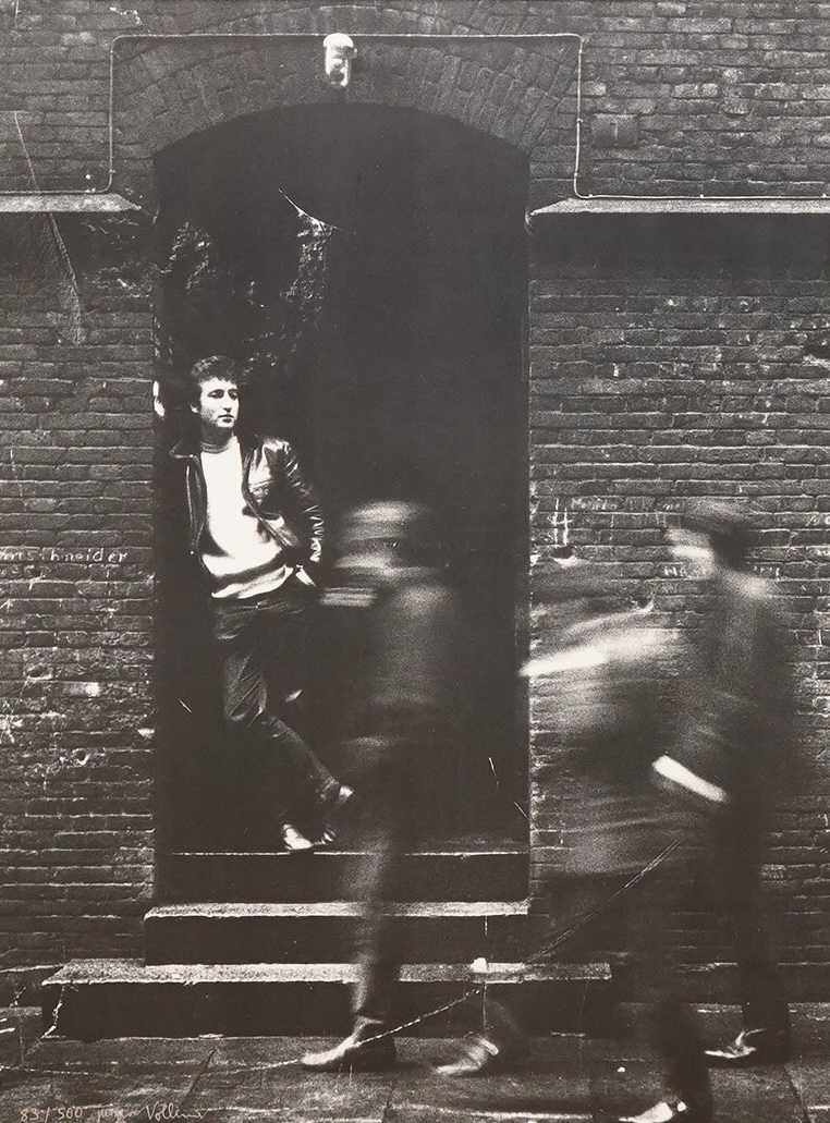 Jurgen Vollmer (German, b.1939), a framed signed limited edition lithograph 83/500 of John Lennon standing in a doorway in Hamburg (glass missing), 79 x 59cm